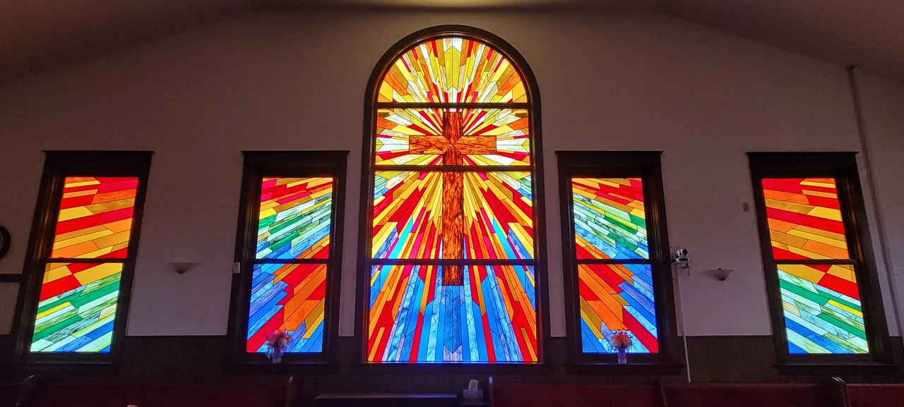 A cross in the brilliant stained-glass sanctuary windows of Progressive Missionary Baptist Church.
